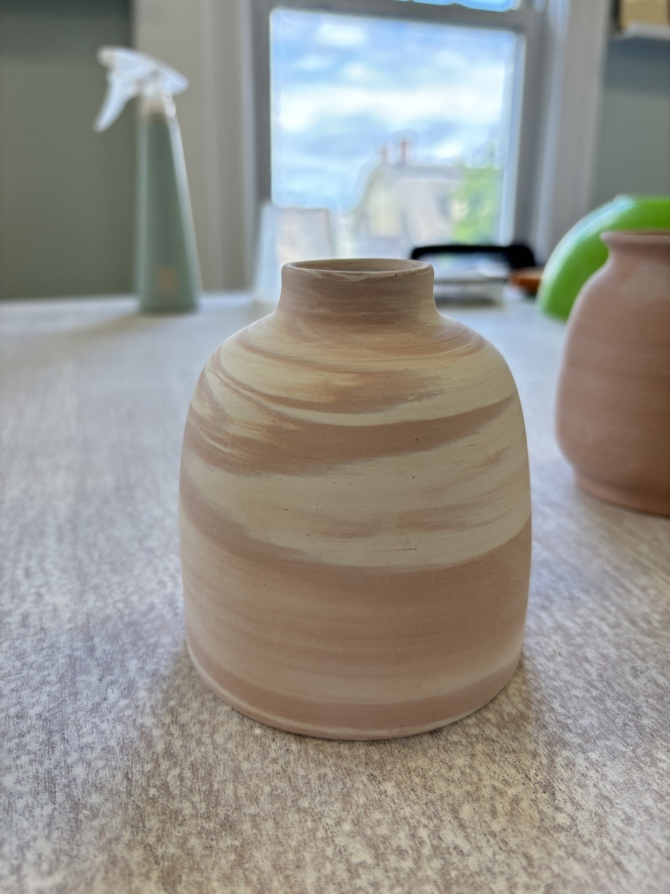 A handmade bud vase in marbled cream and blush clay
