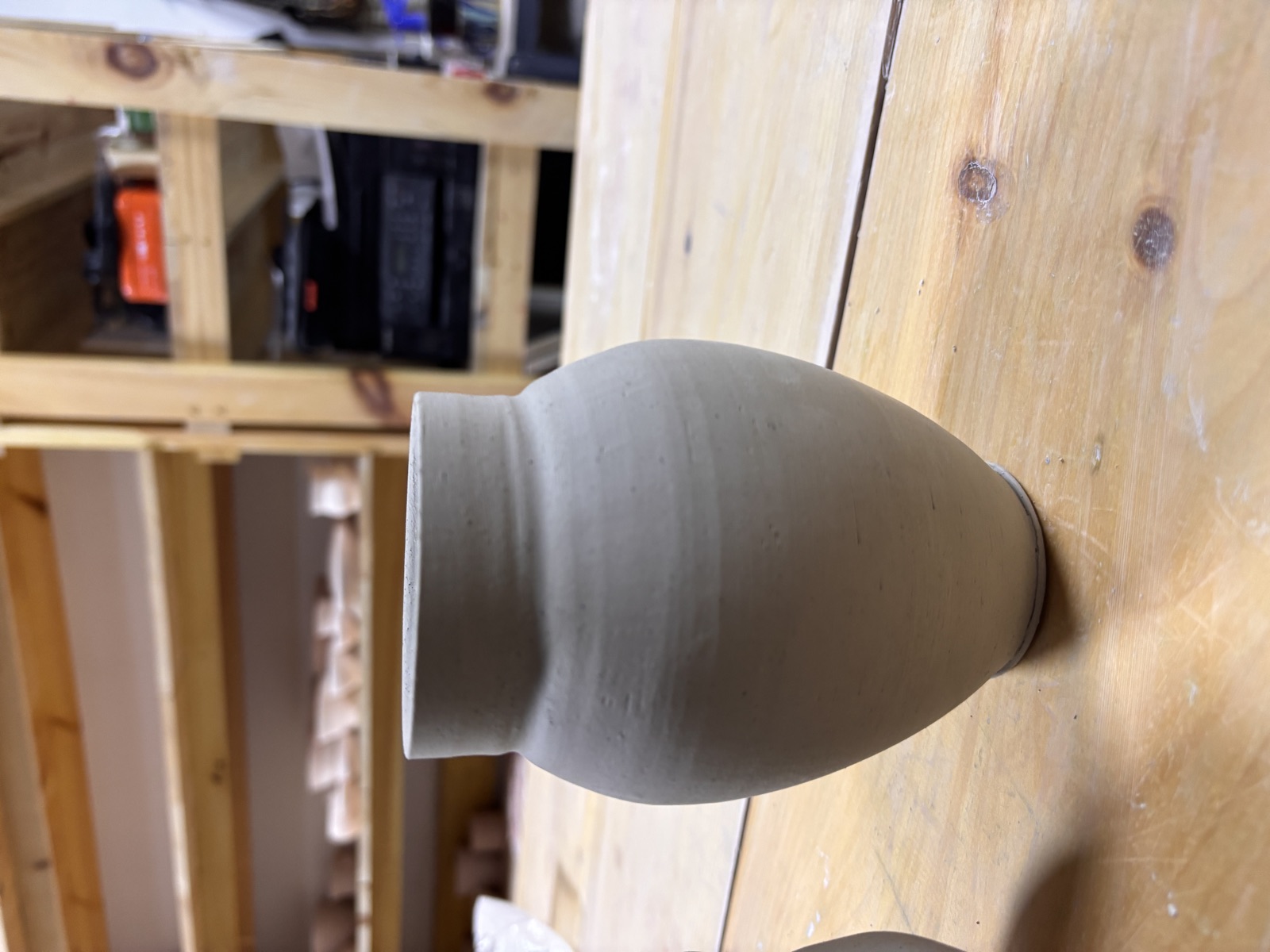 Tall vase, greenware on wooden shelf