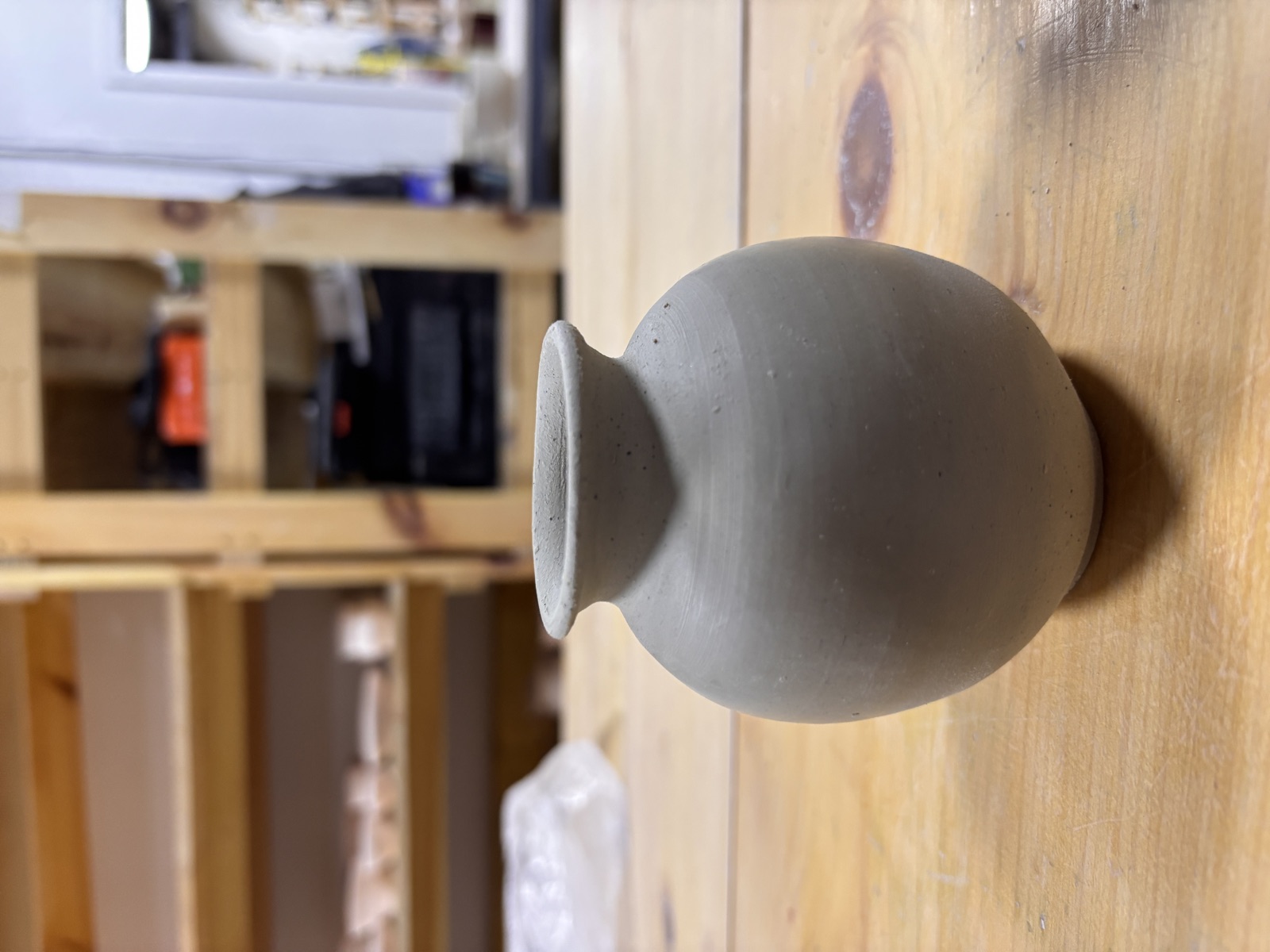 Round bud vase, greenware on wooden shelf